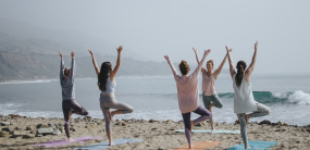 Women doing yoga near a beach